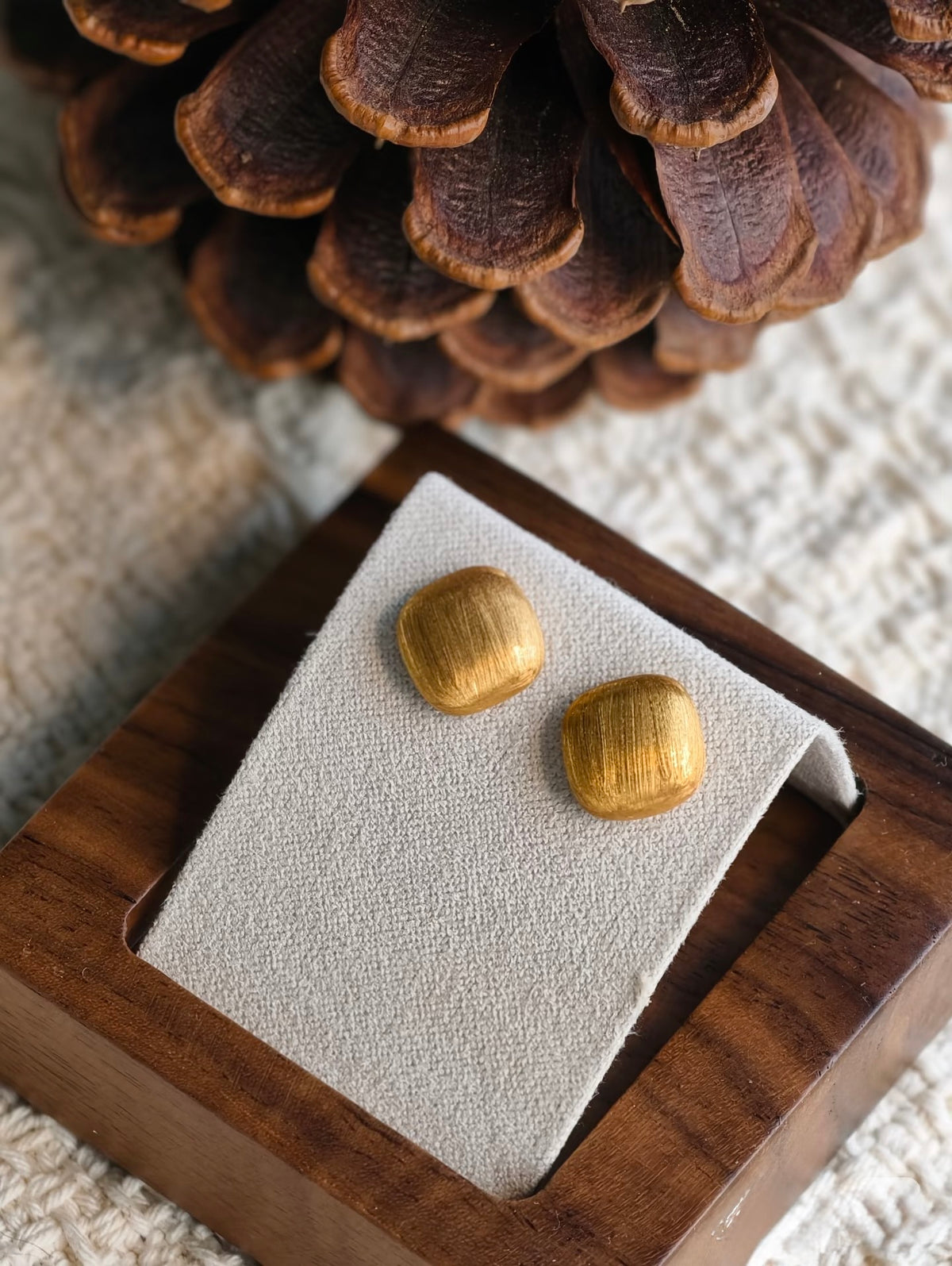18K brushed gold square stud earrings on display