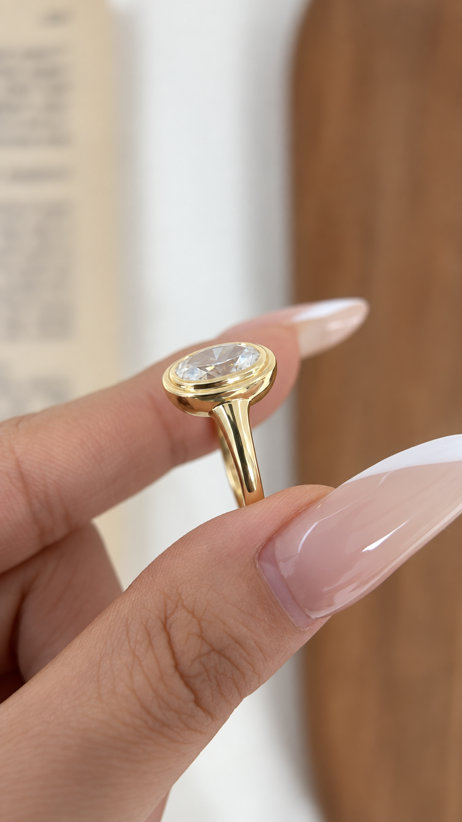 Angled view of oval bezel diamond ring in yellow gold