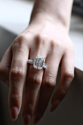 Emerald-cut lab-grown diamond trilogy ring with tapered baguette side stones, worn on hand, view 1