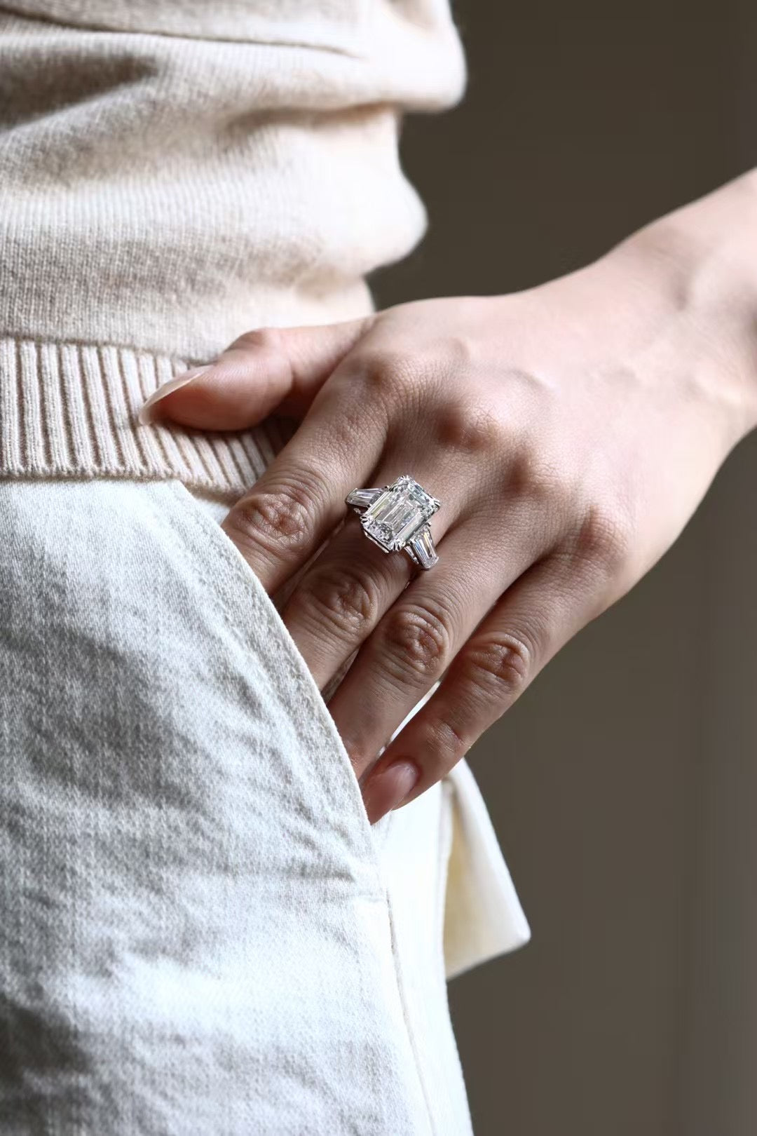 Emerald-cut lab-grown diamond trilogy ring with tapered baguette side stones, worn on hand, view 2