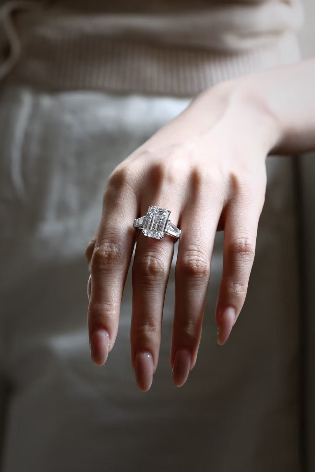 Emerald-cut lab-grown diamond trilogy ring with tapered baguette side stones, worn on hand, view 3