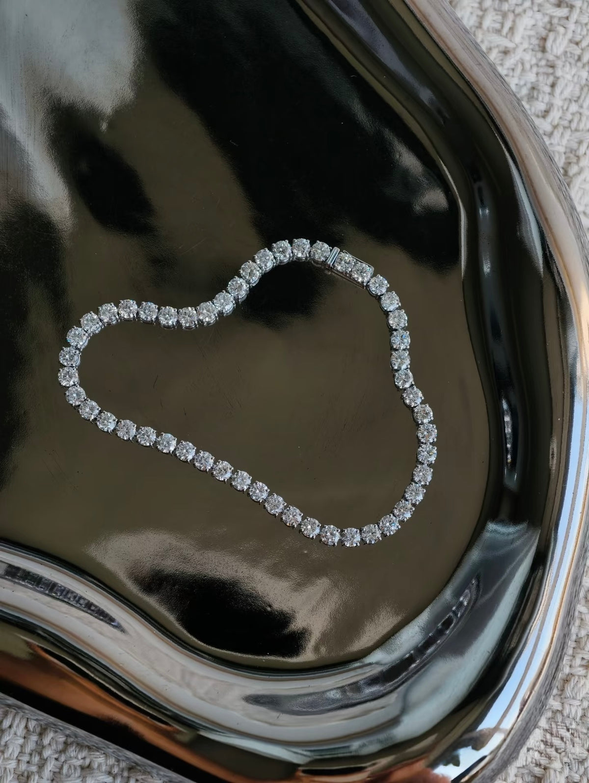 Round lab-grown diamond tennis bracelet on silver tray
