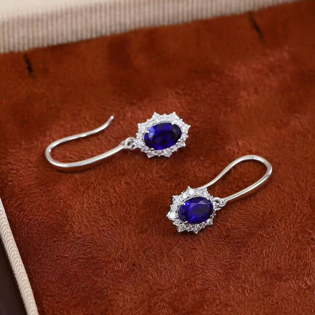 Oval royal blue sapphire earrings with lab-grown diamond halos in 18K gold