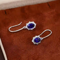 Oval royal blue sapphire earrings with lab-grown diamond halos in 18K gold